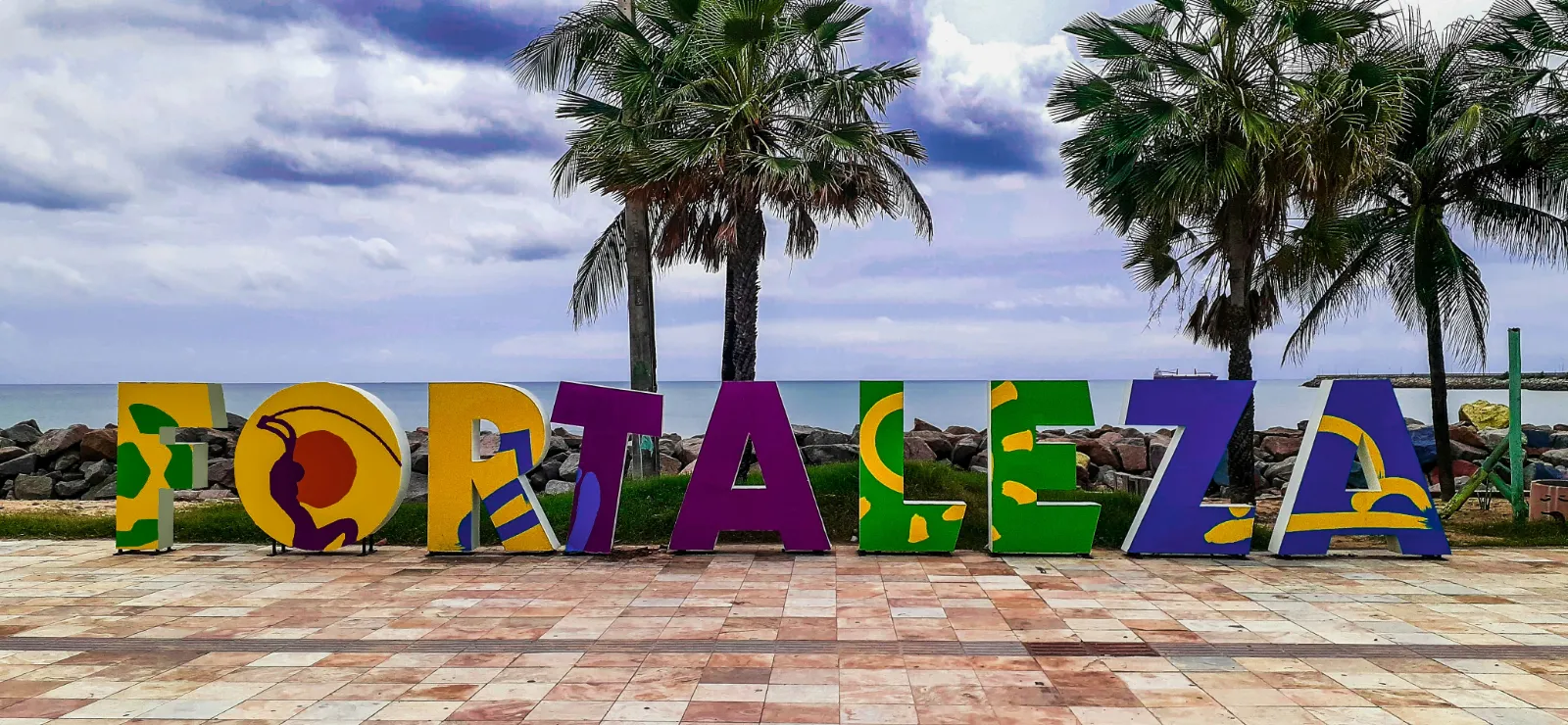 Praia de Iracema e Avenida Beira-Mar em Fortaleza ao entardecer, com a orla e os prédios ao fundo