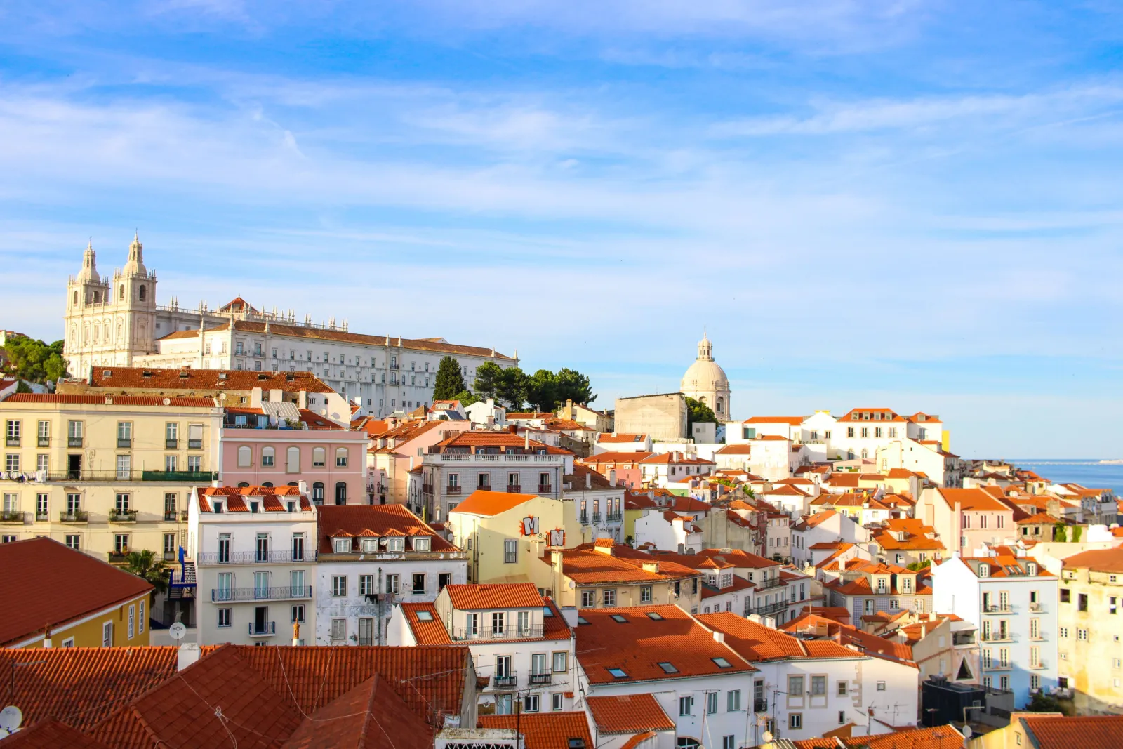 Yellow tram and red rooftops of Alfama with the Tagus River in Lisbon